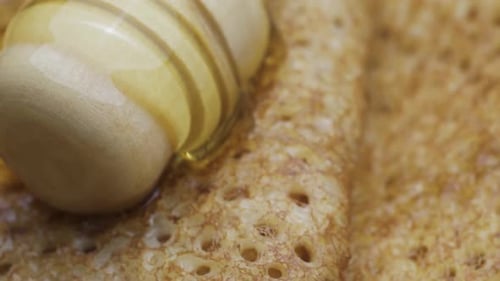 Close-up slide shot. Pour honey over pancakes.