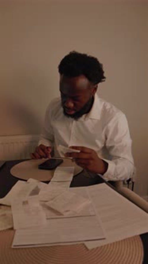 Vertical Video Of Black Male Sorting Through Bill Receipts At Home