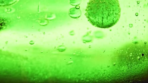 macro shot of sparkling green bubbles falling to ground in bright green water