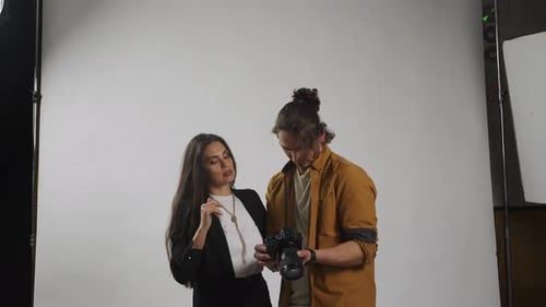 Model and Production Team in the Studio Man Photographer and Woman Model Checking Photos on Camera