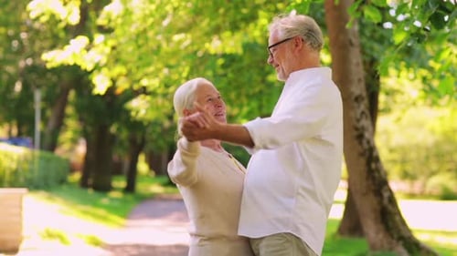 Senior Couple Holding Hands and Dancing in Park