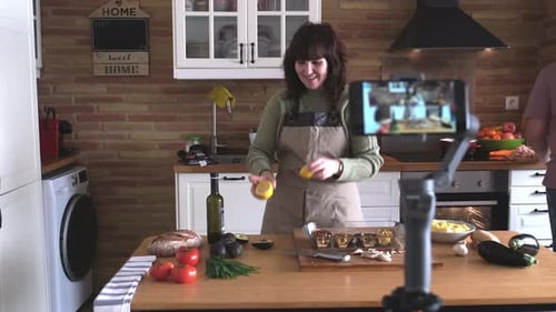 Joven mujer explicando cómo cocinar guacamole a la cámara y graba un Vídeo con su smartphone