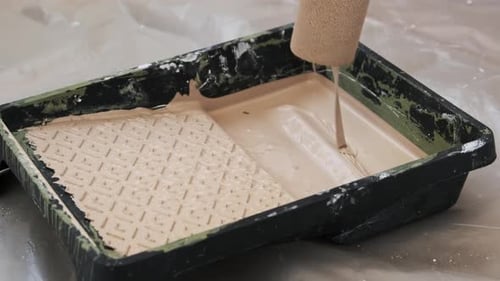 Beige Paint Roller Dipped Into Paint Tray