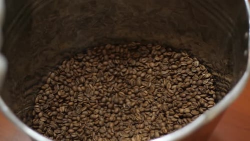 Gloved Hand Scooping Roasted Coffee Beans From Tin