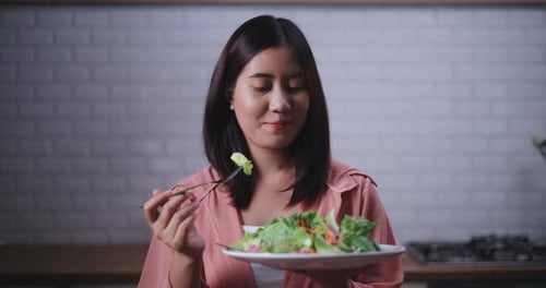 Woman Eating Salad in Kitchen