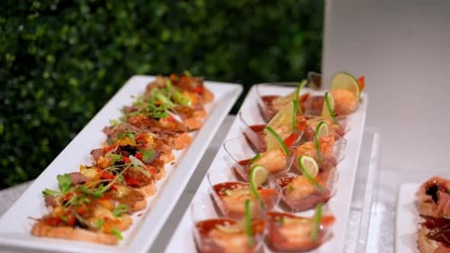 Captura de mesa con cámara móvil con una variedad de aperitivos gourmet que se muestran ordenadamente en soportes de vidrio coloridos