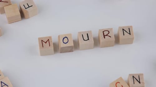Wooden Blocks Spelling Mourn on White Background