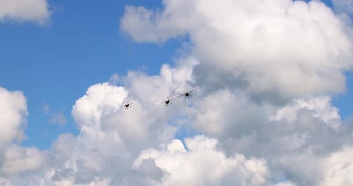 Klassische leichte Propellerflugzeuge fliegen an einem sonnigen blauen Himmel mit weißen Wolken