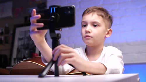 Closeup Boy aprende a tocar la guitarra usando cursos en línea en su aplicación de teléfono