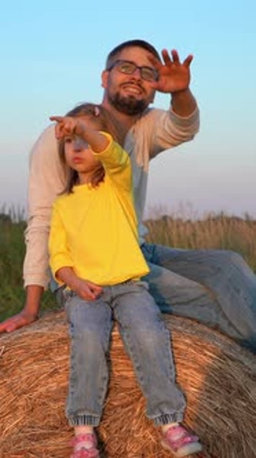 Father and Child Sit in Haystack in Summer Field Countryside Agriculture