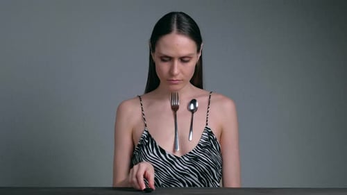 Femme magnétique avec des cuillères attachées à sa peau