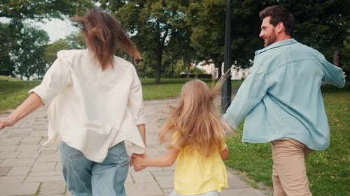 Family Runs Hand in Hand Through Area of City with Trees