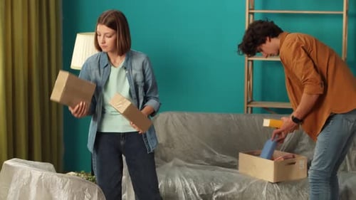 Close Up of Living Room Couple Man and Woman Unpacking Boxes with Stuff in New Apartment Talking