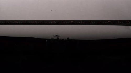 Typewriter Types the Word Fake on Paper