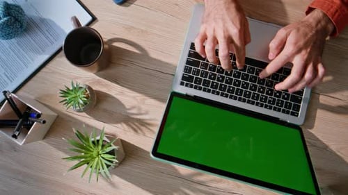 Typing on Laptop with Green Screen Display at Desk