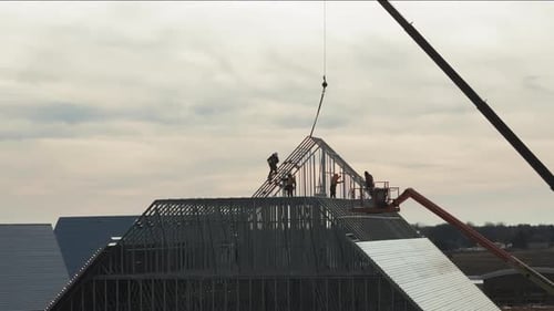 Dachdecker, die ein Dach auf einem Industriegebäude oder einer Lagerhalle installieren, Luftaufnahmen am Tag