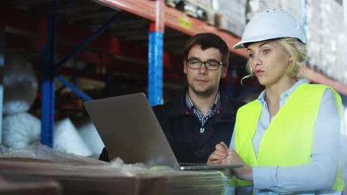 Workers of Warehouse are Working Together on Laptop. Wears White Hard Hat.