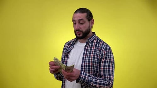 Man Counting Currency in Front of Yellow Background