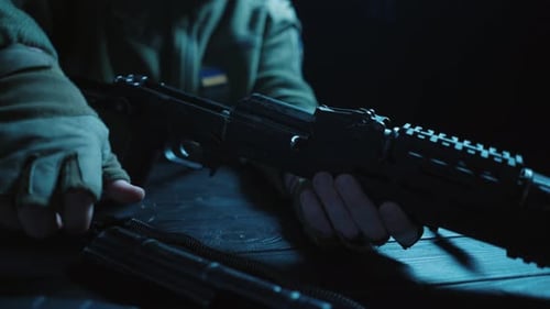 Montage de tous les détails du fusil d'assaut Kalachnikov sur une table en bois, gros plan des mains d'un homme