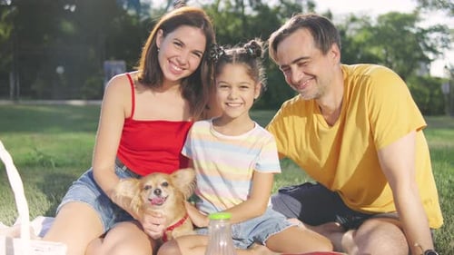 Happy Family with Dog Enjoys Picnic in Park