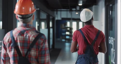 A Group of Construction Workers Engaged in Tasks Within a Hallway of a Building Site