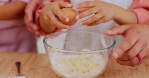 Child Cracking Egg into Mixing Bowl with Adult Help