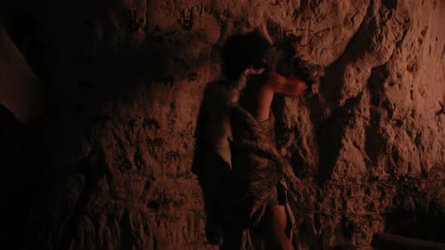 Ancient Man Carving Cave Art by Firelight