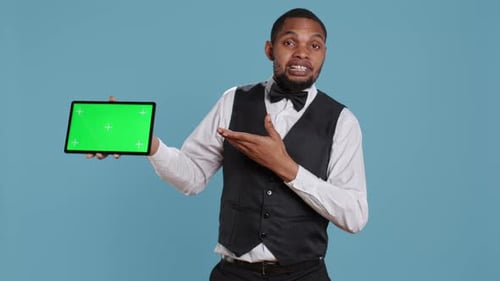 Doorkeeper Bellboy Poses with Green Screen on Tablet at the Hotel Reception