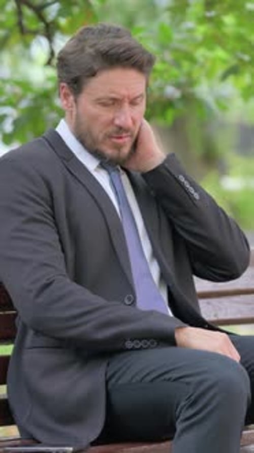 Man in Suit Sitting on Bench Outdoors
