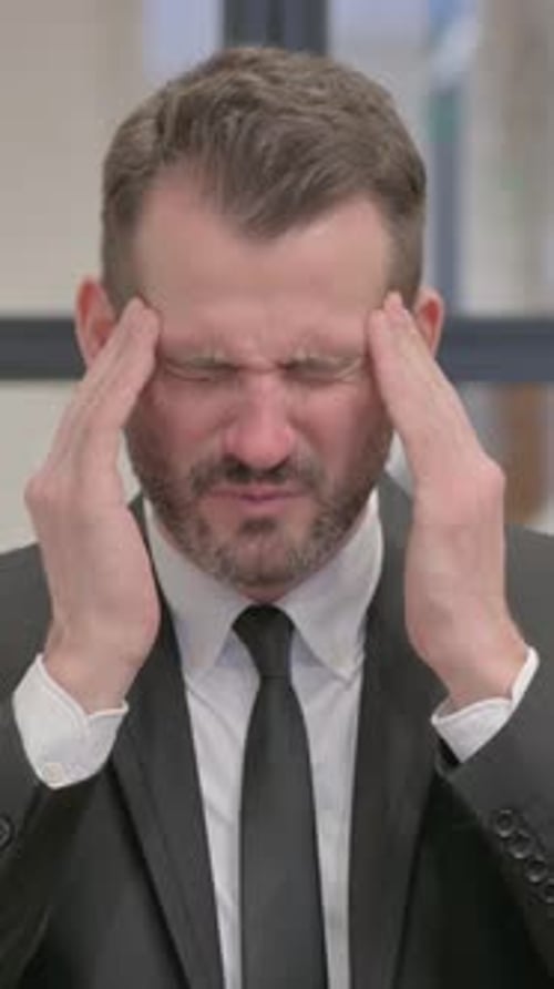 Man in Suit Holding Head in Pain