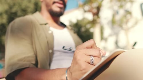 Close-up of the hand of young student writing with pen in notebook