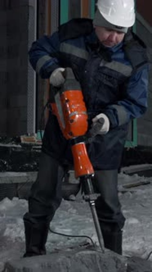 Man Drills Holes in a Concrete Block Clip Industrial Background of a Builder at the Construction