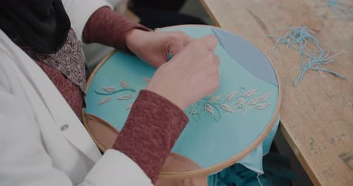 Woman Embroidering Fabric with Blue Thread