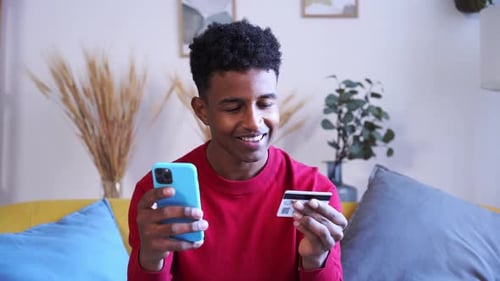 Young Man Shopping Online with Smartphone and Card