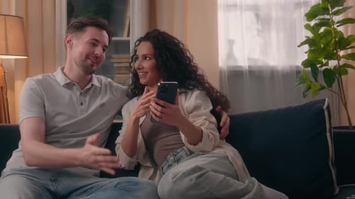 Couple Relaxing Together on Sofa with Smartphone