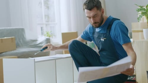 Un ouvrier d'assemblage de meubles qui réussit utilise un tournevis pour assembler une étagère et consulte les instructions. Prof