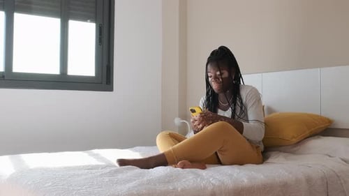 Woman Using Smartphone on Bed in Bedroom