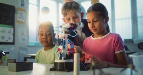 Elementary School Students Studying Model of Innovative Robotic Arm Having Fun
