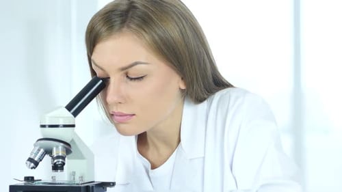 Woman Scientist Using Microscope in Bright Lab
