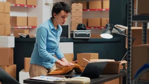 Woman Packs Garment at Warehouse Shipping Desk