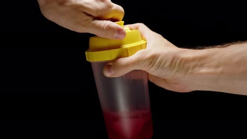 Mixing a Sports Drink in a Shaker and Bringing the Cup Close to Drink. Slow-Motion on Black