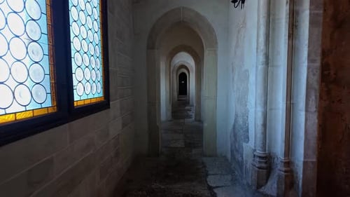 Walking through a medieval stone corridor in the Corvin Castle featuring arched doorways.