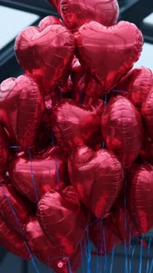 Bunch of Red Heart Balloons Float Near Building