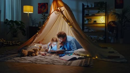 Father and Child Reading Book in Cozy Home Tent