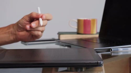 Hand Uses Stylus on Tablet at Desk