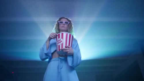 Femme joyeuse dansant en mangeant du pop-corn en regardant un concert sur un projecteur