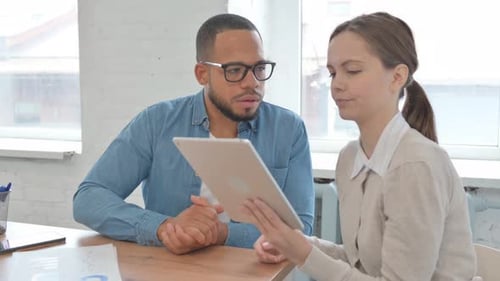 Man and Woman Discussing Tablet in Office