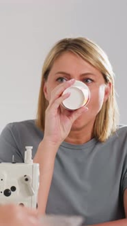 Frau trinkt Kaffee, Frau macht eine Pause mit dampfender Tasse, Person, die sich an der Nähstation mit einem Getränk entspannt