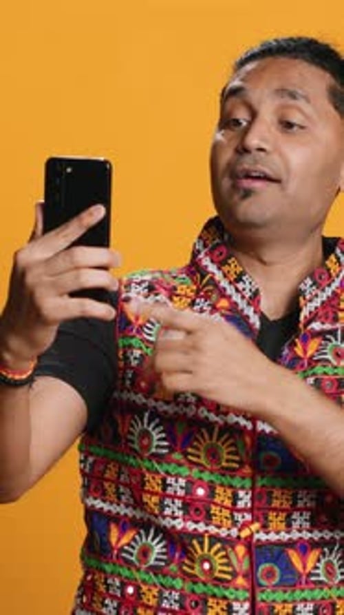 Vertical Video Joyous Man Greeting Friend Over Online Videocall on Cellphone Studio Background