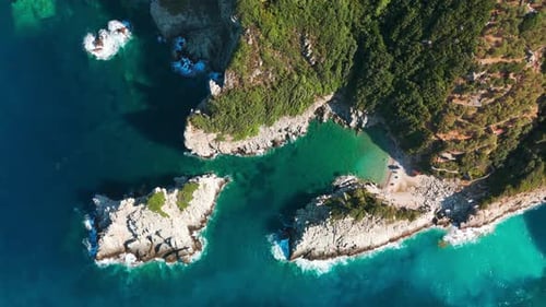 A rocky coastline with turquoise waters and lush greenery on a sunny day, aerial view